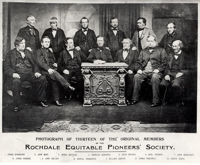 Dertien van de oorspronkelijke oprichters van de Rochdale Society of Equitable Prioneers, de eerste succesvolle verbruikscoöperatie. Onbekende fotograaf, Photograph of Thirteen of the Original Members of the Rochdale Equitable Pioneers' Society (1865). Bron: Wikimedia Commons